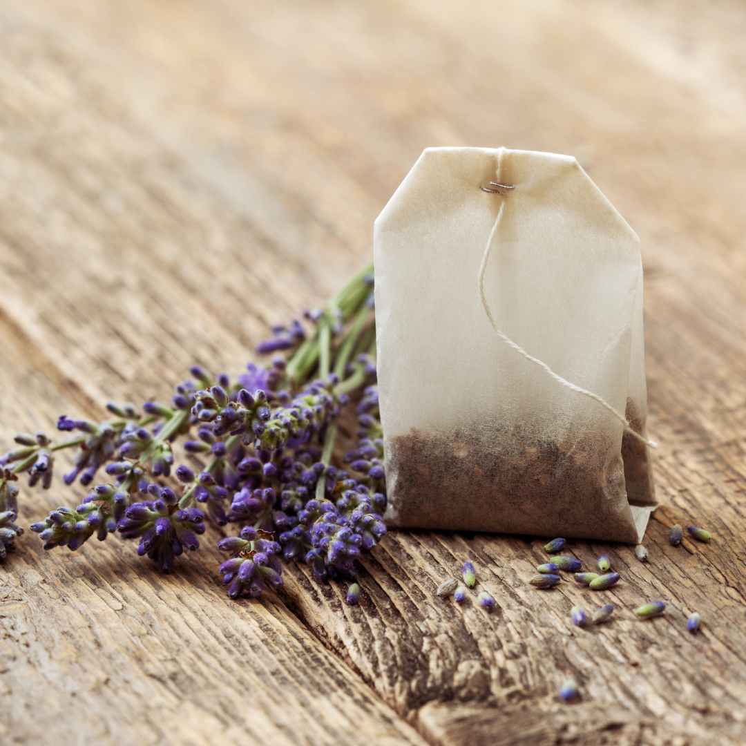 Teebeutel neben Lavendelblüten auf einem Holztisch