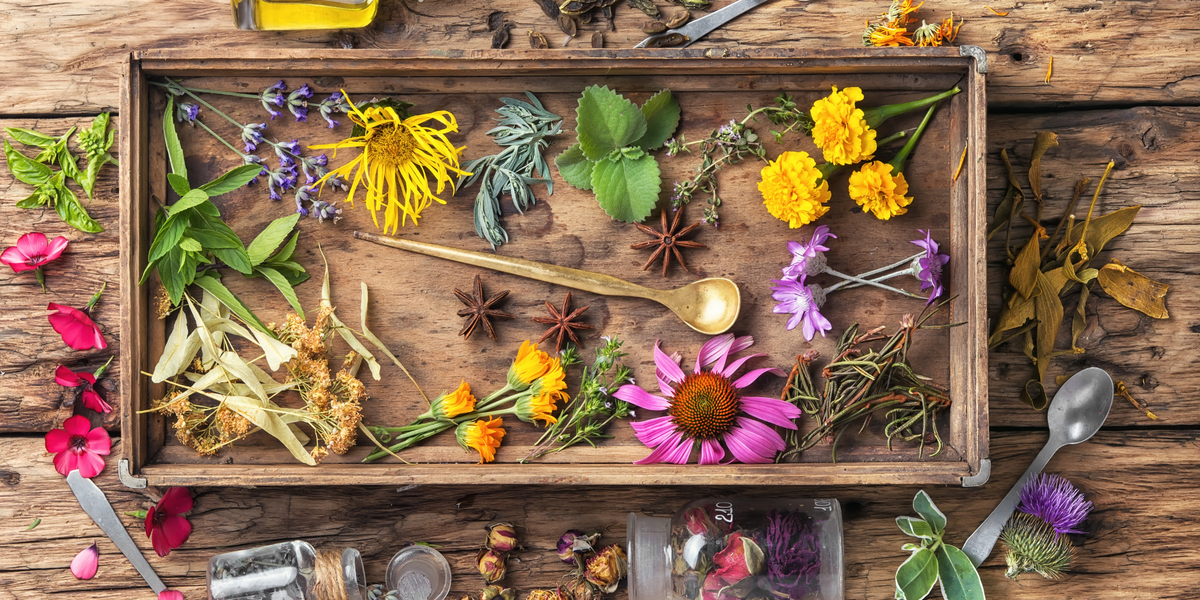 Kräuter und bunte Blüten auf einem Holztablett